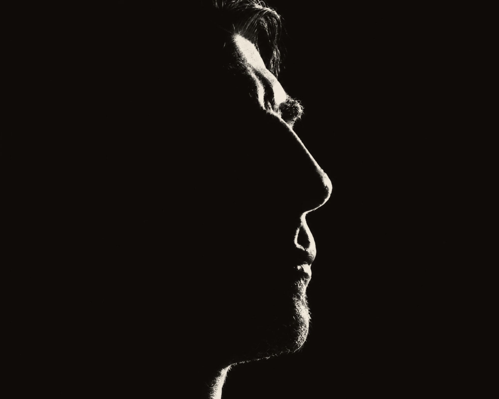 Haig V. in profile, his face traced by a single light against black.