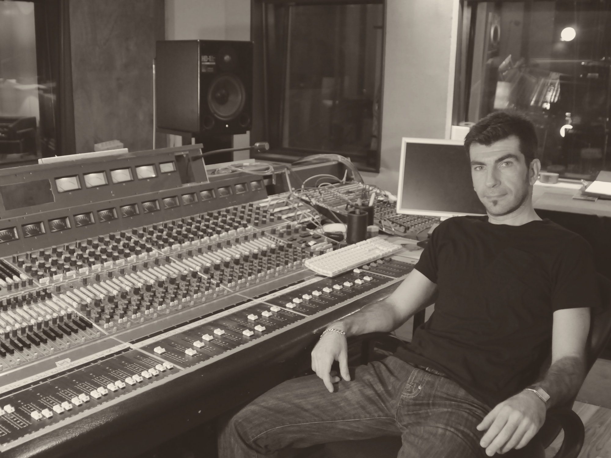 Haig V. seated beside a large mixing console in a studio, looking into the camera.